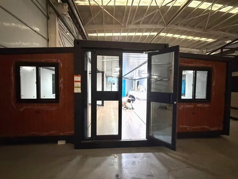 Workers assembling expandable container house in factory