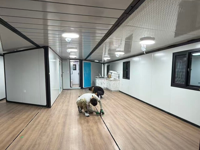 Workers decorate container house in factory